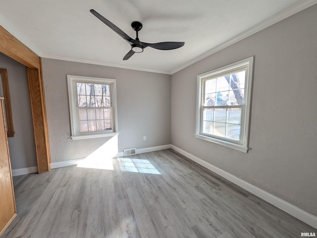 spare room featuring ceiling fan, ornamental molding, a healthy amount of sunlight, and light hardwood / wood-style floors