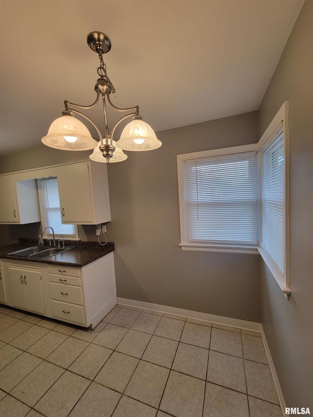 kitchen with light tile patterned floors, decorative light fixtures, sink, and white cabinets