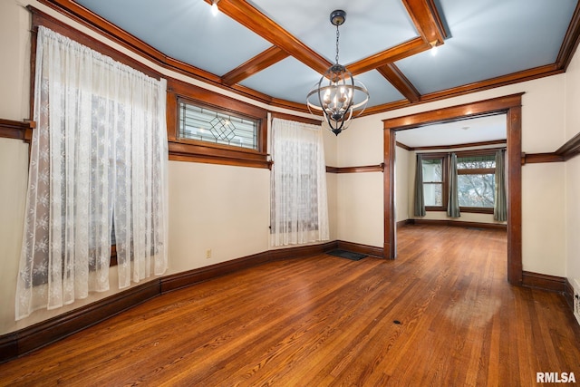 empty room with an inviting chandelier, coffered ceiling, crown molding, dark wood-type flooring, and beam ceiling