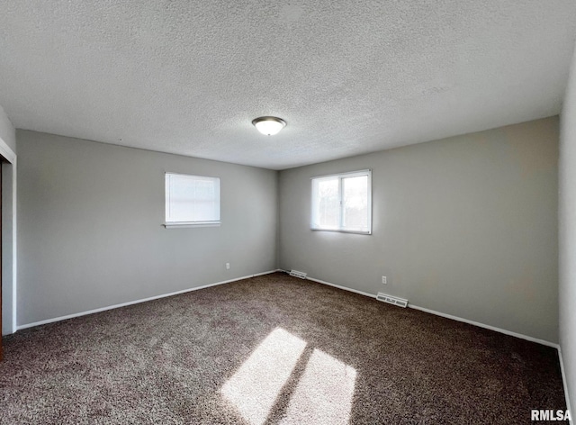 unfurnished room featuring dark carpet and a textured ceiling