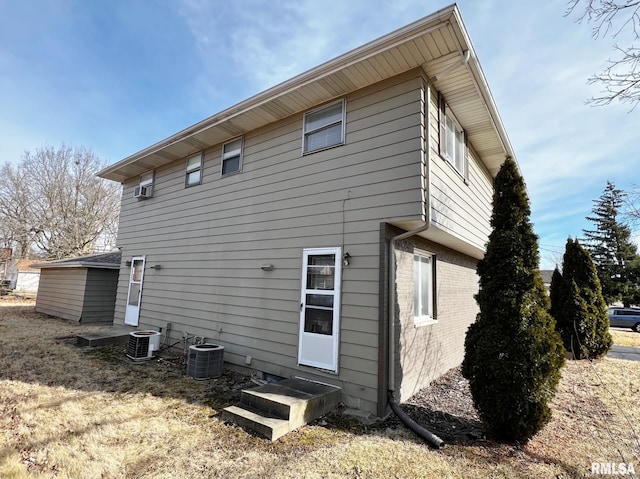 rear view of house with central AC and a lawn