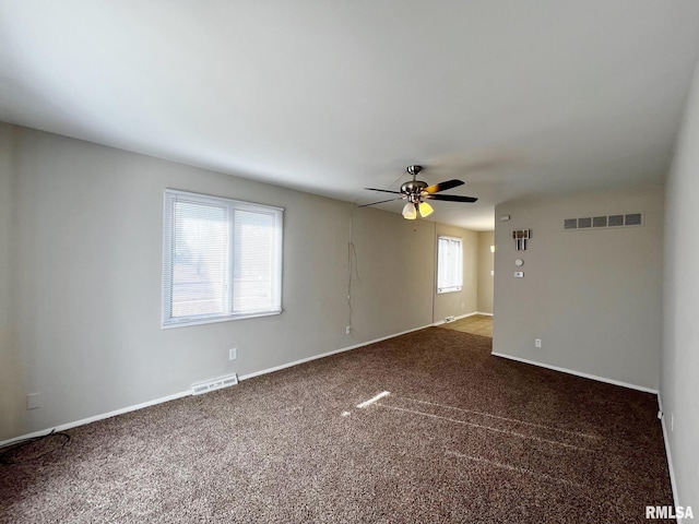 empty room featuring ceiling fan and dark colored carpet