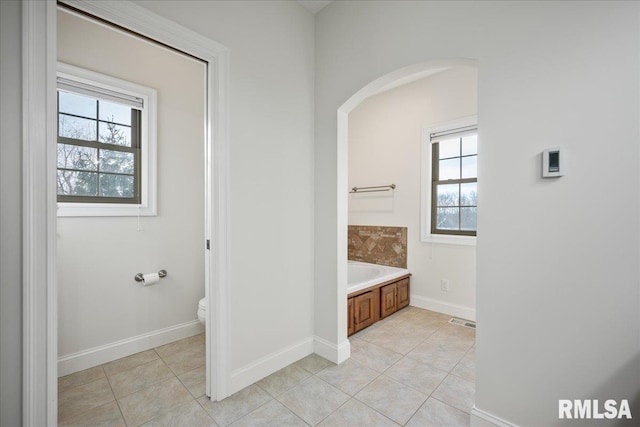 bathroom featuring a tub, tile patterned floors, and toilet