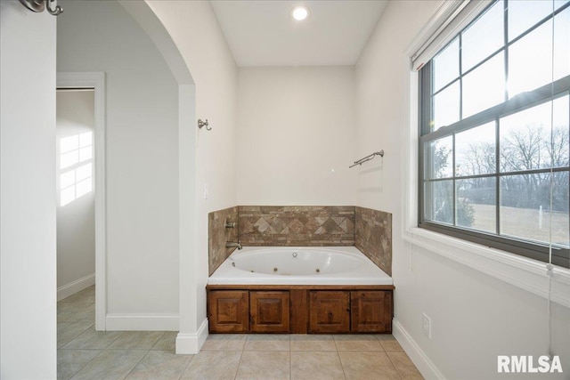 bathroom featuring a wealth of natural light, tile patterned floors, and a tub