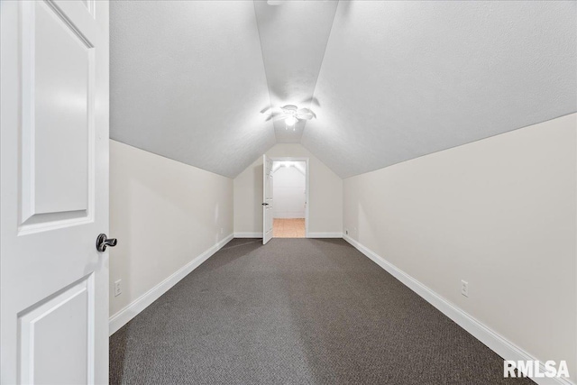 bonus room featuring vaulted ceiling and dark colored carpet