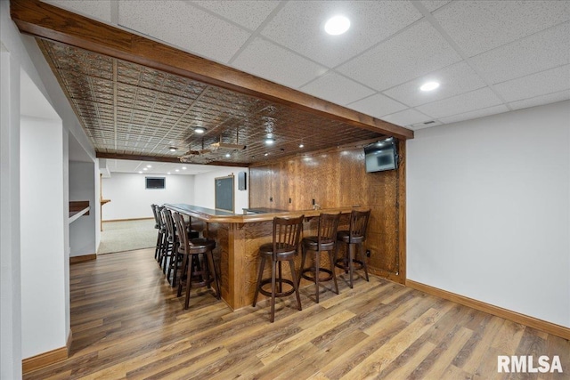 bar with hardwood / wood-style floors and a drop ceiling