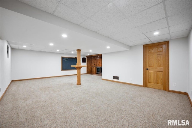 basement with a paneled ceiling and carpet flooring