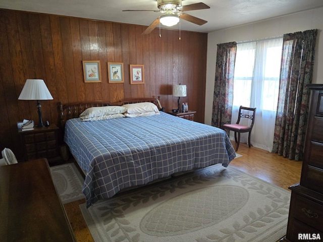 bedroom featuring hardwood / wood-style flooring, wooden walls, and ceiling fan