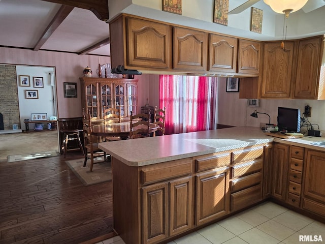 kitchen with light hardwood / wood-style flooring, beam ceiling, and kitchen peninsula