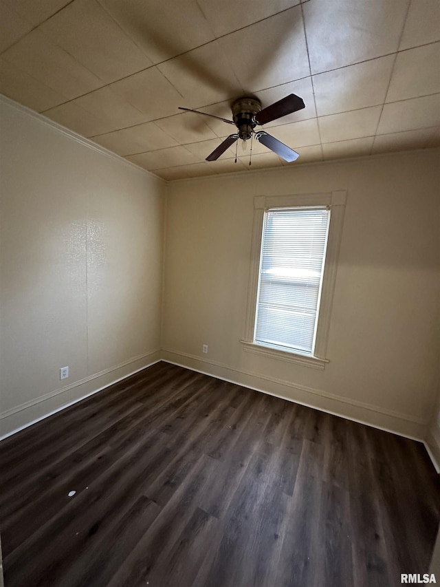 empty room featuring dark wood-type flooring, ceiling fan, and ornamental molding