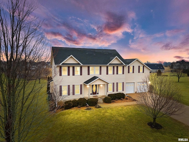 colonial-style house featuring a front lawn, concrete driveway, and an attached garage