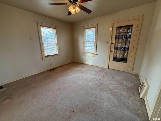 empty room featuring light carpet, a wealth of natural light, and ceiling fan