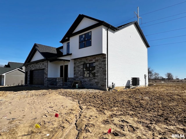 exterior space featuring stone siding, central AC unit, and a garage