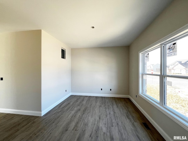 empty room featuring visible vents, baseboards, and dark wood-type flooring