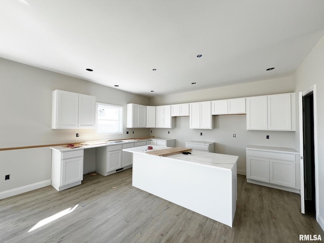 kitchen featuring baseboards, white cabinetry, a center island, and light wood-style floors