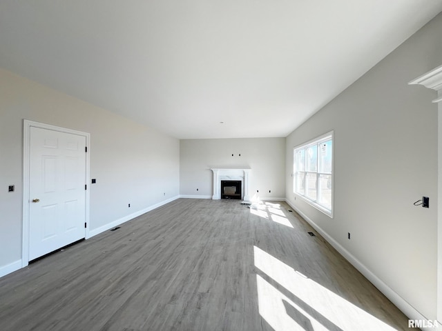 unfurnished living room with wood finished floors, a fireplace, and baseboards