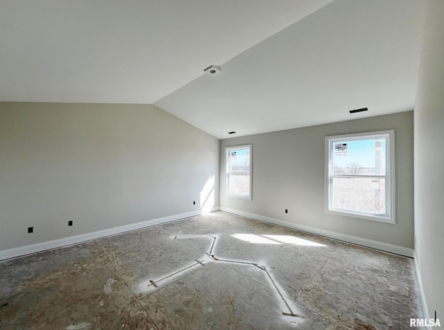 unfurnished room featuring baseboards and vaulted ceiling