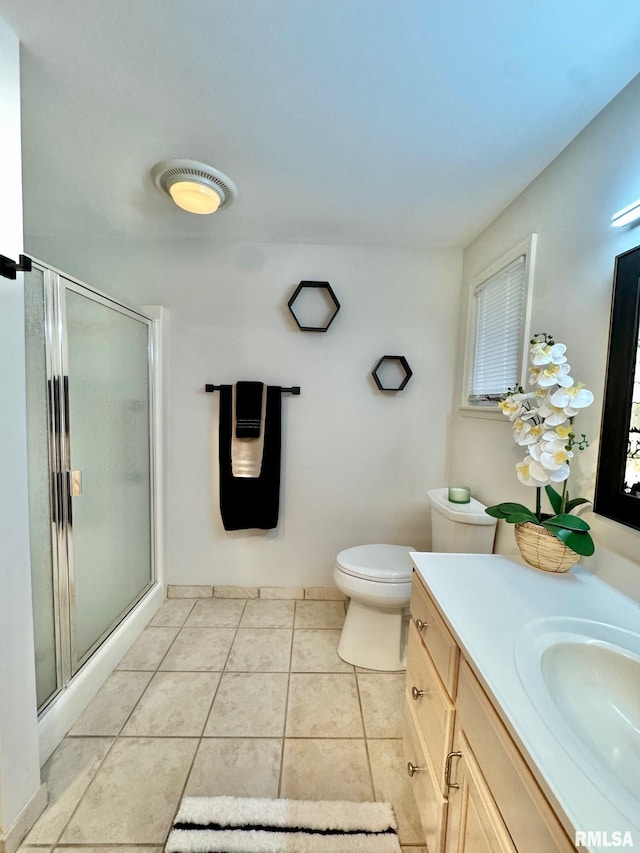 bathroom featuring tile patterned flooring, vanity, an enclosed shower, and toilet