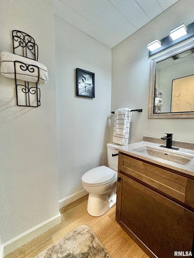 bathroom with wood-type flooring, toilet, and vanity