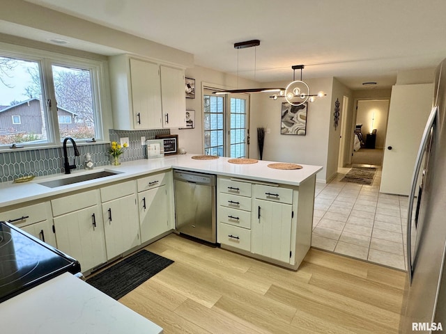 kitchen featuring decorative light fixtures, tasteful backsplash, dishwasher, sink, and kitchen peninsula