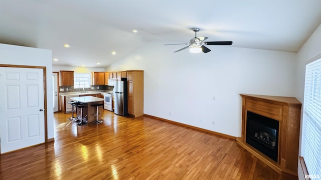 living room with hardwood / wood-style flooring, vaulted ceiling, and ceiling fan