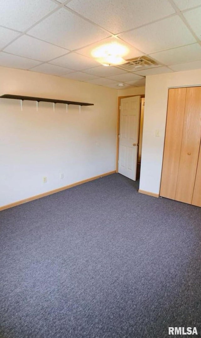 carpeted empty room with a drop ceiling