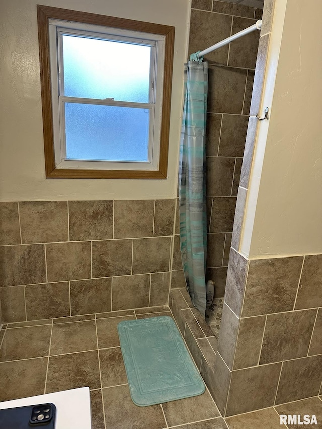 bathroom featuring a shower with curtain and tile walls