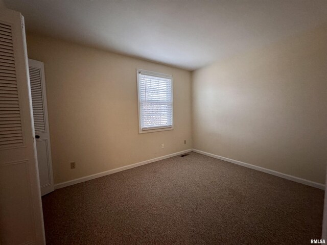 unfurnished room with dark colored carpet