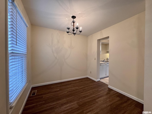 unfurnished dining area featuring a chandelier and dark hardwood / wood-style flooring