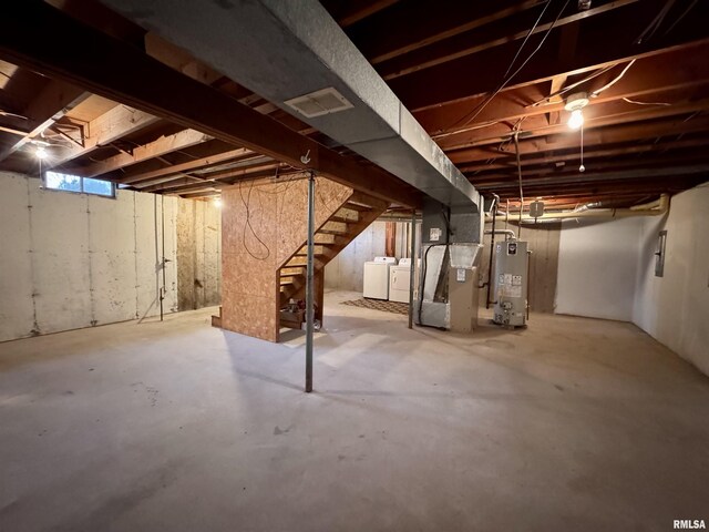 basement with gas water heater, heating unit, and washing machine and clothes dryer