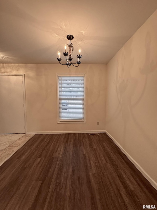 unfurnished dining area featuring dark hardwood / wood-style flooring and a chandelier