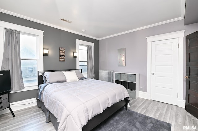 bedroom featuring ornamental molding, radiator, and light wood-type flooring