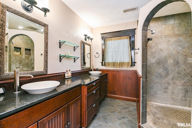 bathroom with vanity, tiled shower, and wood walls