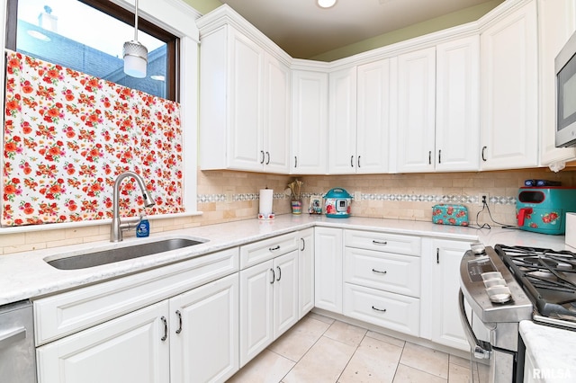 kitchen featuring sink, appliances with stainless steel finishes, tasteful backsplash, white cabinets, and decorative light fixtures