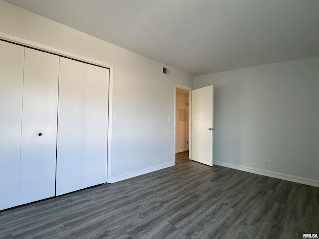 unfurnished bedroom with dark hardwood / wood-style flooring and a closet