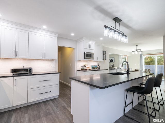 kitchen featuring white cabinets, sink, a center island with sink, and stainless steel microwave