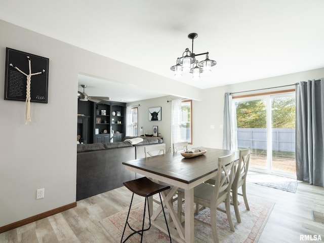 dining space with ceiling fan with notable chandelier and light hardwood / wood-style flooring