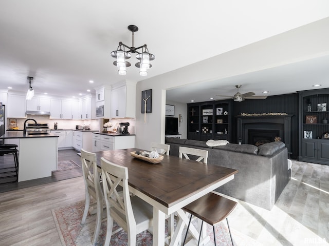 dining area featuring ceiling fan with notable chandelier and light hardwood / wood-style floors