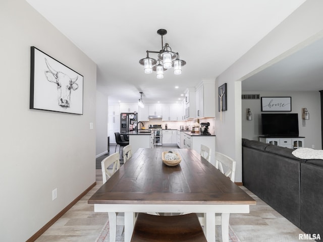 dining area featuring sink, an inviting chandelier, and light hardwood / wood-style floors