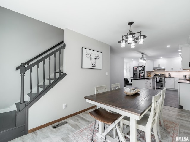 dining room featuring sink, light hardwood / wood-style flooring, and a chandelier