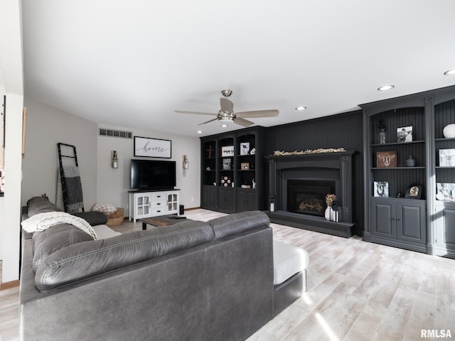 living room featuring hardwood / wood-style flooring, ceiling fan, and built in shelves