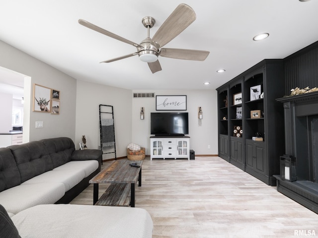 living room featuring built in shelves, ceiling fan, and hardwood / wood-style floors