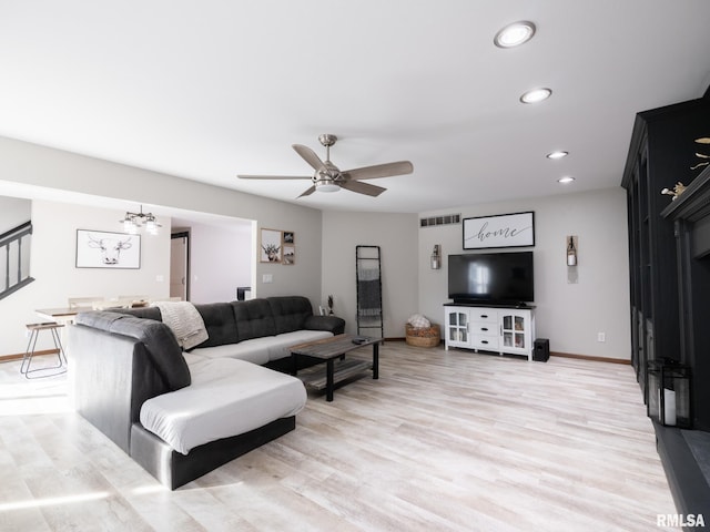 living room with wood-type flooring and ceiling fan with notable chandelier