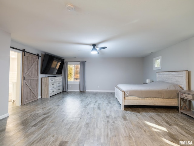 unfurnished bedroom featuring a barn door, hardwood / wood-style floors, and ceiling fan