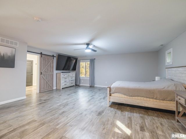 bedroom featuring ceiling fan, wood-type flooring, and a barn door