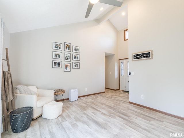 sitting room with ceiling fan, beam ceiling, high vaulted ceiling, and light wood-type flooring