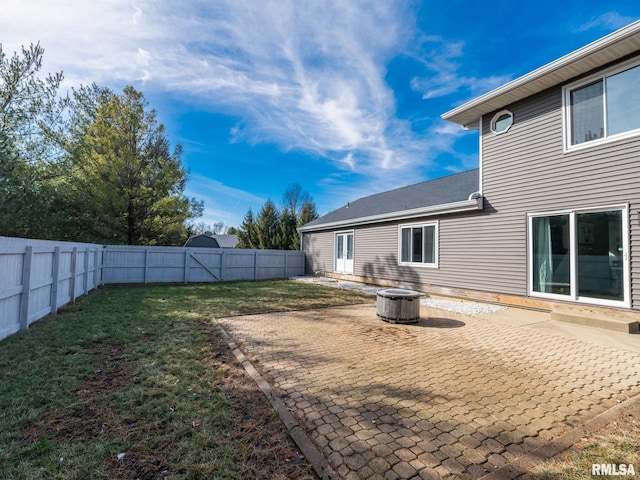 rear view of property with a fire pit, a patio area, and a lawn