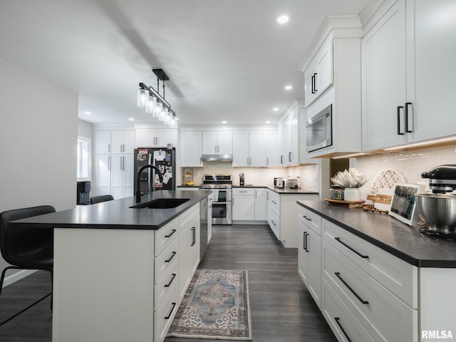 kitchen featuring sink, white cabinetry, hanging light fixtures, an island with sink, and stainless steel appliances