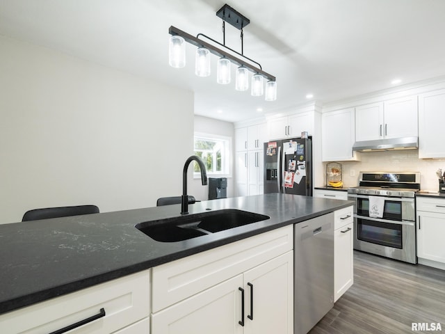 kitchen with sink, white cabinetry, hanging light fixtures, stainless steel appliances, and decorative backsplash