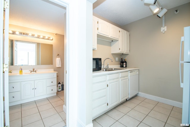 kitchen with white cabinetry, sink, light tile patterned floors, and white appliances